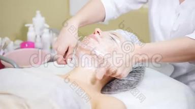 美容师包装在电影客户`的下巴做美容程序清洗脸在美容诊所。